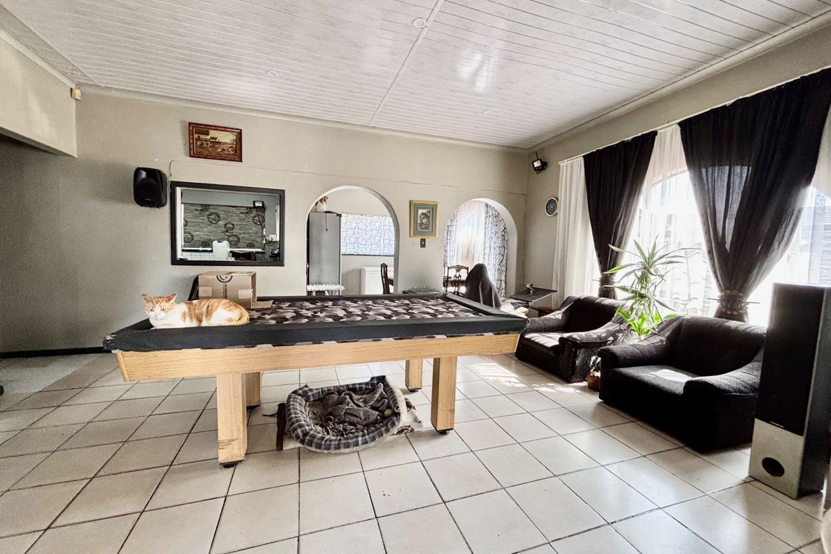 Spacious living area featuring tiled flooring, tongue and groove ceiling, and distinctive archway transitions to adjacent rooms.