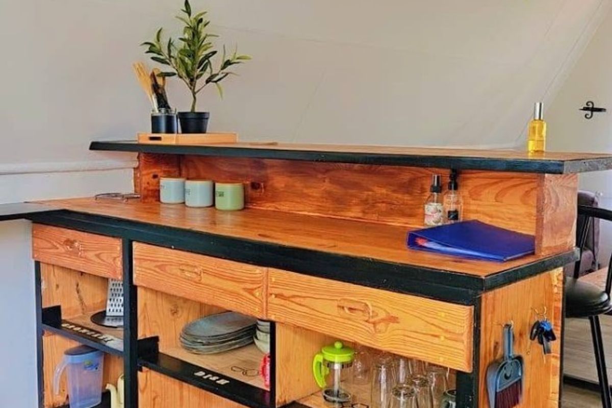 A custom-built timber kitchen island featuring open shelving and a suspended wooden lighting fixture, providing a rustic and functional workspace.