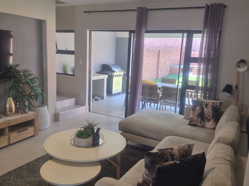 A comfortable living room featuring tiled flooring, a recessed wall niche, and large sliding glass doors that provide seamless access to the outdoor patio area.