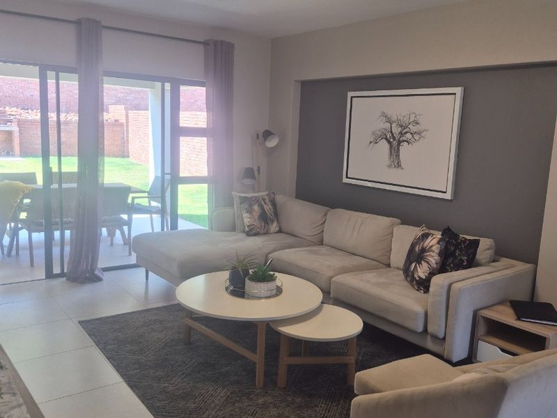 A bright and well-maintained living room featuring large sliding glass doors that provide direct access to the outdoor patio and garden area.
