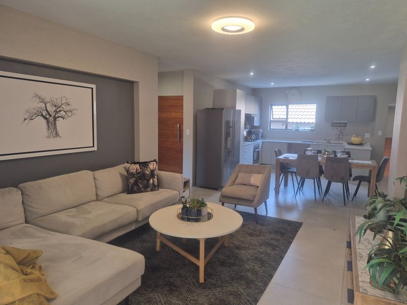 Spacious open-plan living area featuring a modern kitchen with built-in cabinetry, tiled floors, and seamless flow between the lounge and dining space.