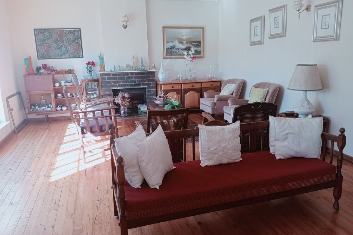A spacious living room featuring original timber flooring and a classic brick fireplace, offering a warm and traditional atmosphere.