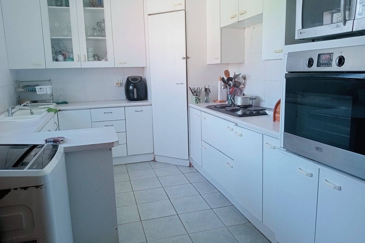 A functional kitchen featuring white cabinetry, built-in oven and microwave, gas hob, and tiled flooring with ample counter space.