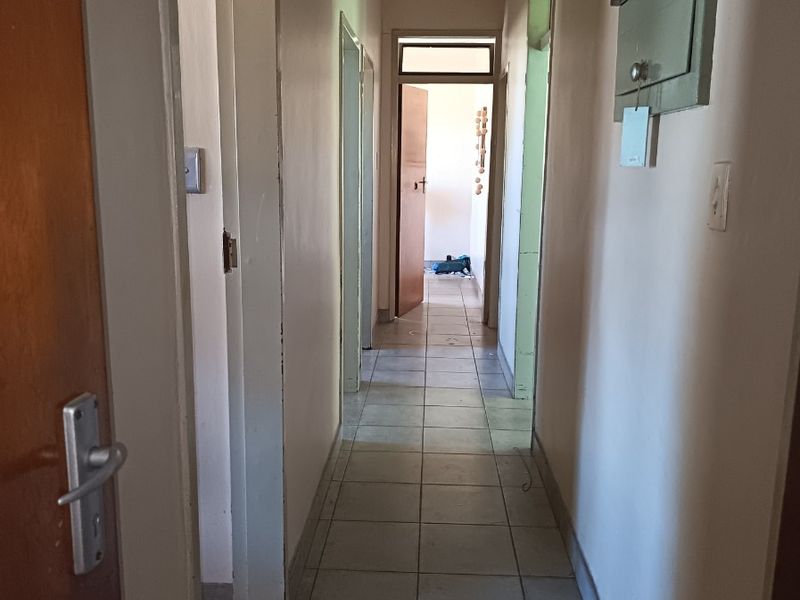 A functional hallway featuring tiled flooring and an exposed electrical distribution board, providing access to multiple rooms within the home.