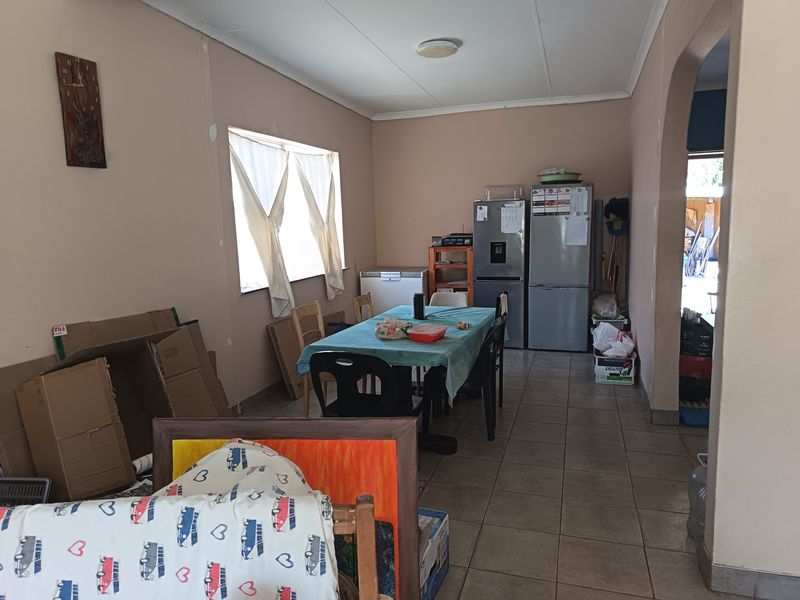 Open plan living and dining area featuring tiled flooring and an arched entryway, requiring cosmetic updates to improve the overall aesthetic.