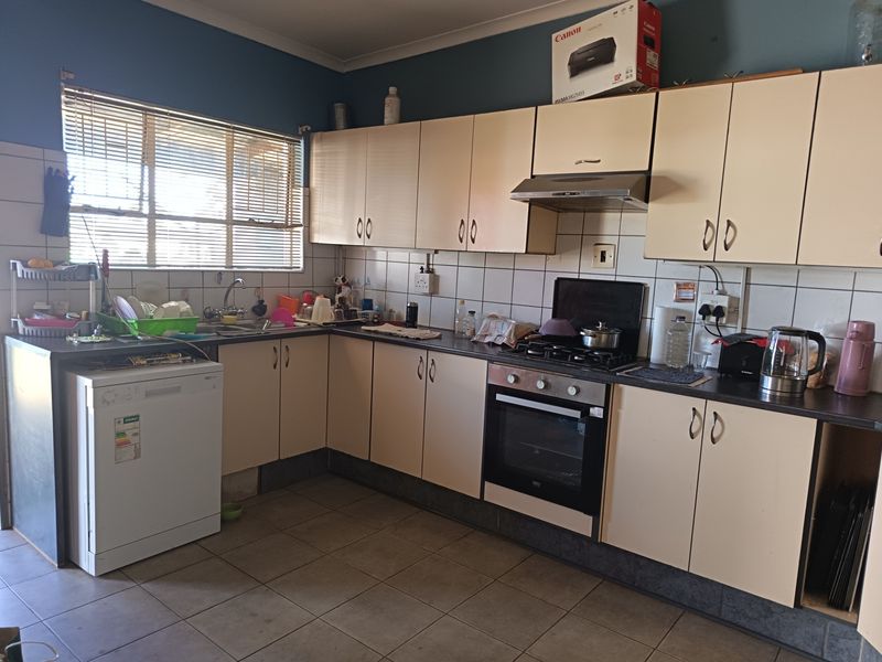 A functional kitchen featuring laminate cabinetry, built-in oven, gas hob, extractor fan, and tiled backsplash, offering a practical layout for daily meal preparation.