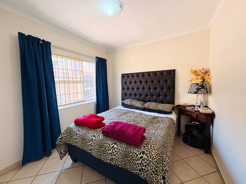 A bedroom featuring tiled flooring, a window with security bars, and coved ceiling detailing.