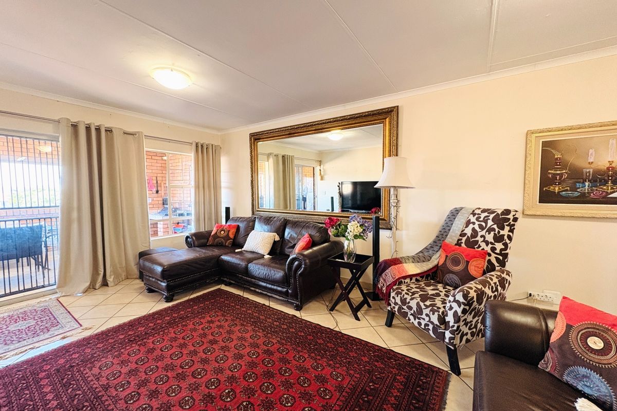 A spacious living room featuring tiled flooring and a large sliding glass door that provides access to an outdoor balcony area.