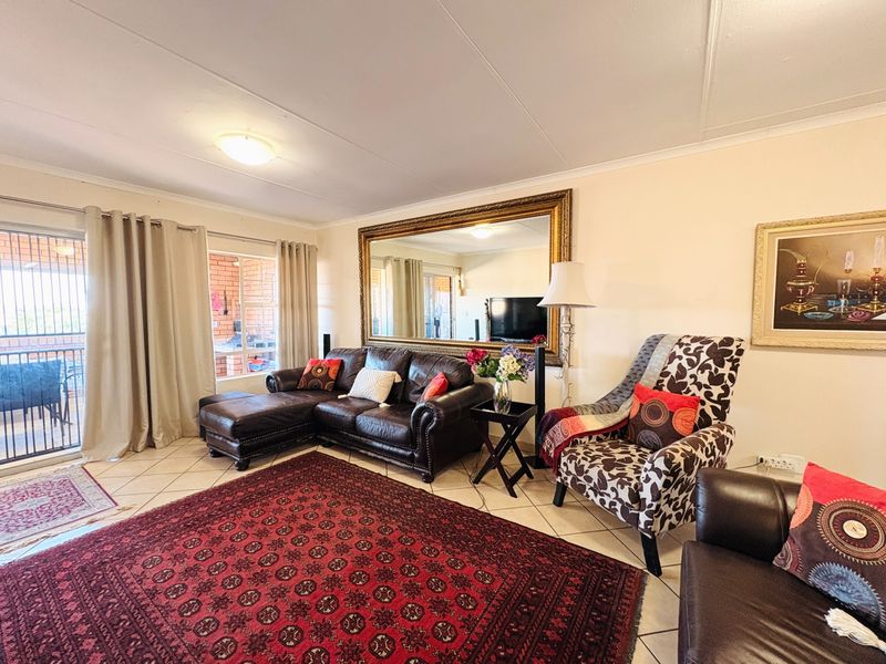 A spacious living room featuring tiled flooring and a large sliding glass door that provides access to an outdoor balcony area.