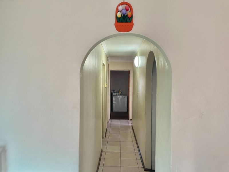 A functional hallway featuring arched doorways and tiled flooring, providing access to the interior living spaces of the home.