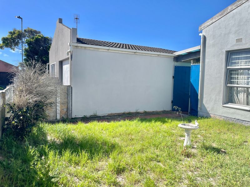 Rear exterior view of the property featuring a small garden area, paved walkway, and standard residential building structure with tiled roofing.