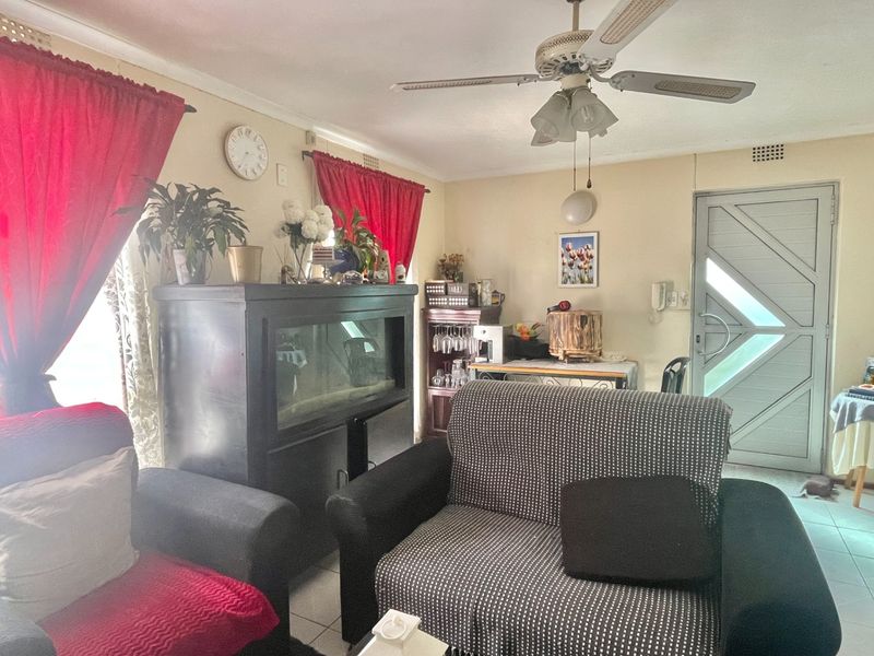 A living room featuring tiled flooring, a ceiling fan, and a secure entrance door, offering a functional space with potential for modernization.
