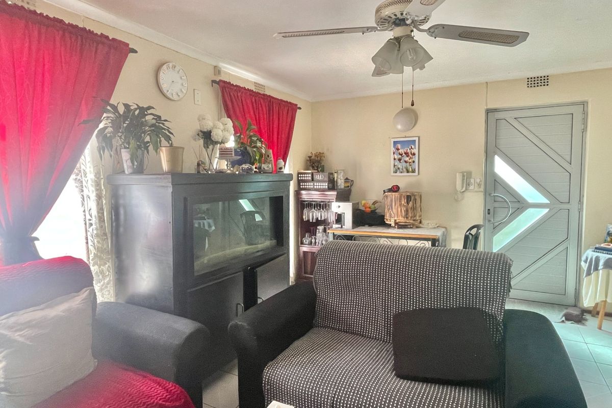 A living room featuring tiled flooring, a ceiling fan, and a secure entrance door, offering a functional space with potential for modernization.