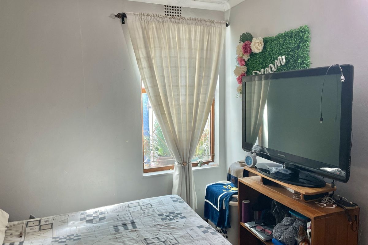A standard bedroom featuring a window with natural light and a built-in ventilation brick.