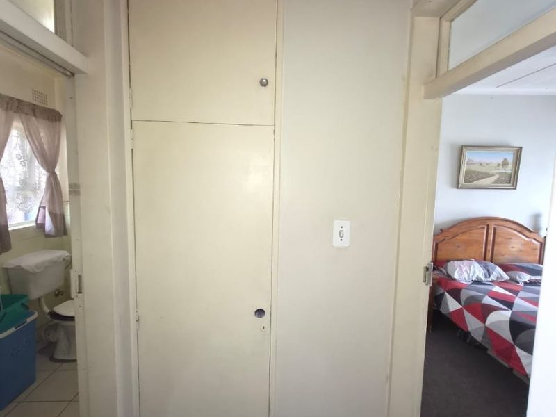 A functional hallway featuring a built-in linen cupboard with transom windows above the adjacent room doorways.