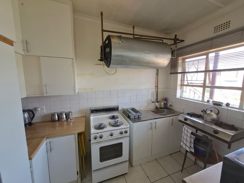 A functional kitchen featuring tiled flooring, built-in cabinetry, a stainless steel sink, and both electric and gas cooking options.