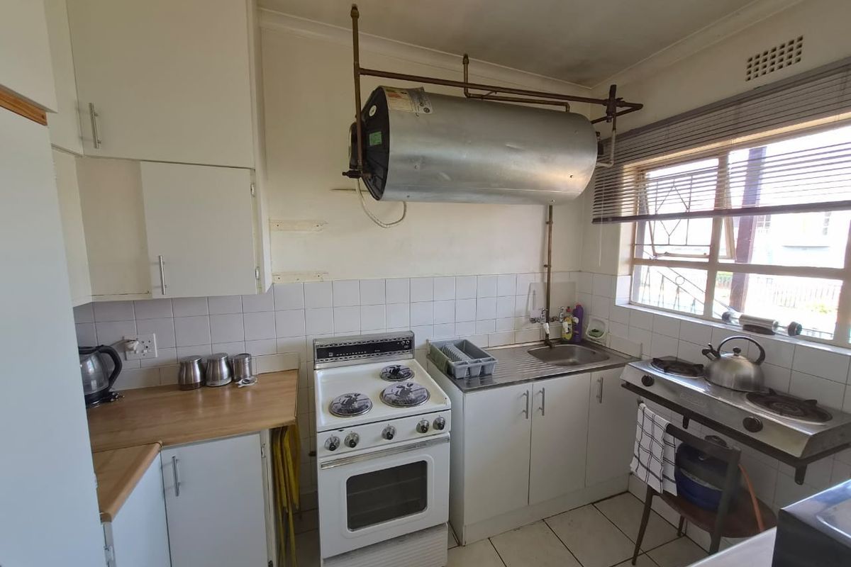 A functional kitchen featuring tiled flooring, built-in cabinetry, a stainless steel sink, and both electric and gas cooking options.