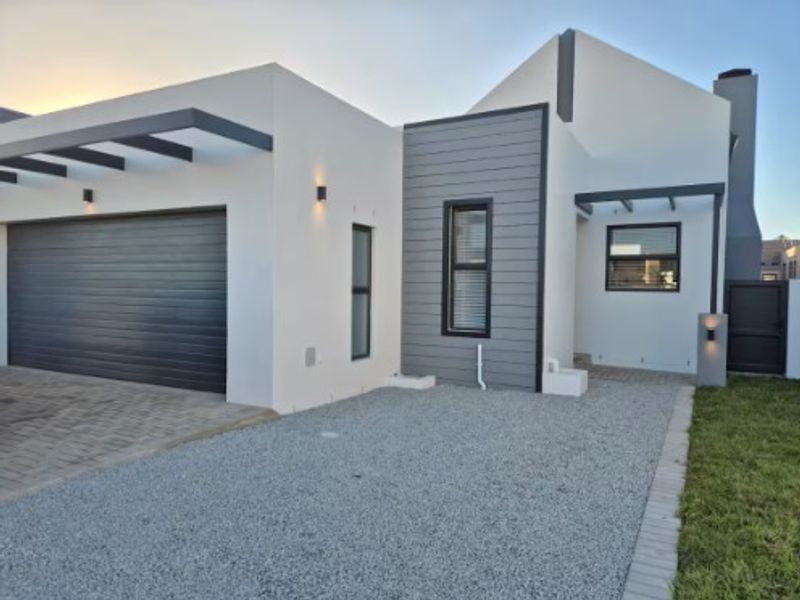 Modern front elevation featuring a double garage, clean architectural lines, timber cladding accents, and a well-maintained paved and gravel driveway.