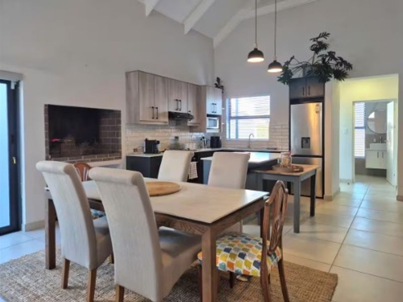Open-plan living and dining area featuring a vaulted ceiling, built-in fireplace, and a modern kitchen with subway tile backsplash and island.