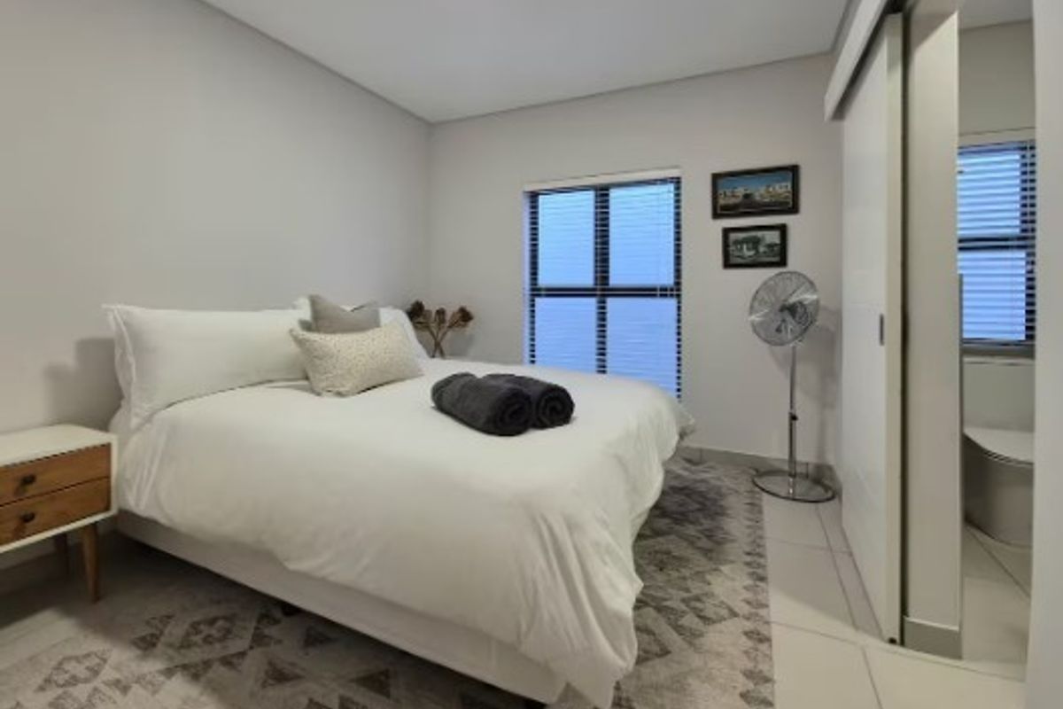 A well-maintained bedroom featuring neutral wall finishes, tiled flooring, and a convenient sliding door providing access to an en-suite bathroom.