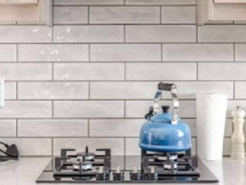 Modern kitchen featuring a built-in oven, gas cooktop, extractor fan, subway tile backsplash, and stone countertops with fitted cabinetry.