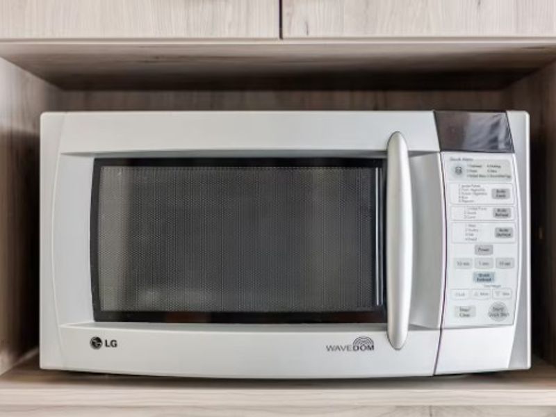 A built-in microwave oven integrated into light wood-tone kitchen cabinetry.