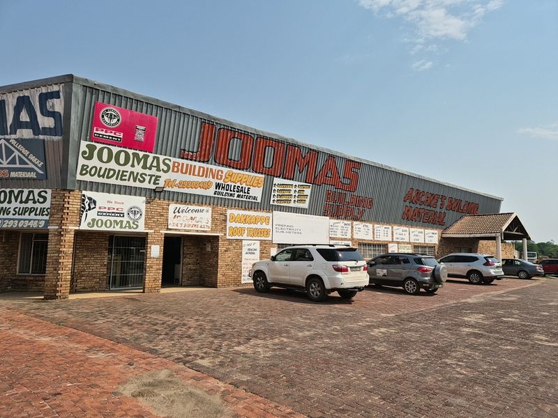 Front elevation of an industrial building featuring corrugated metal cladding, face brick accents, and a paved parking area.