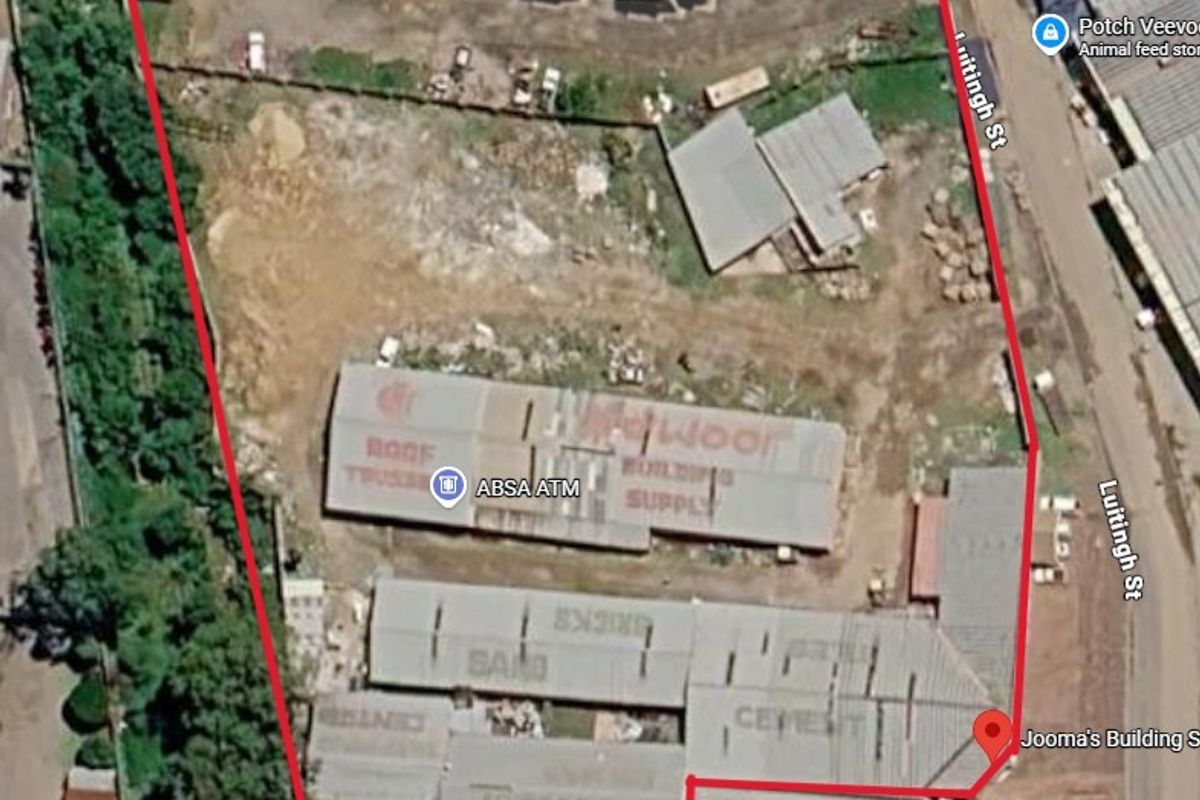 Aerial view of an industrial property featuring multiple warehouse buildings, storage areas, and a fenced yard with street access.