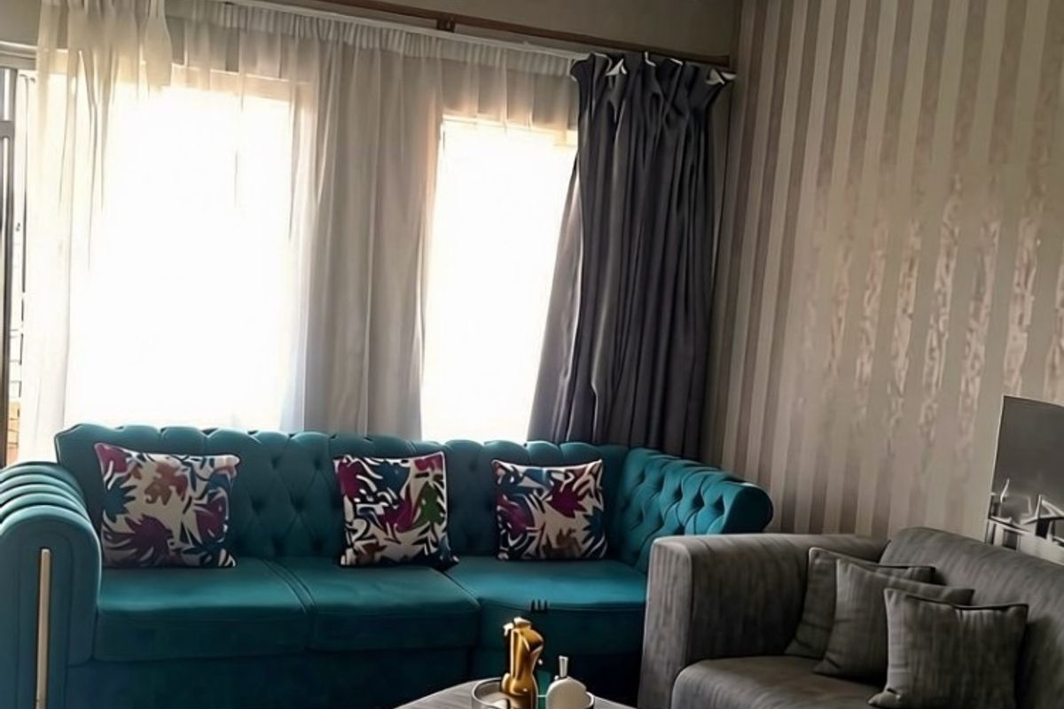A comfortable living room featuring tiled flooring and large windows with curtain tracks, providing ample natural light.