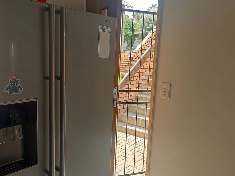 An interior view of an apartment entrance featuring a security gate leading to an external staircase.