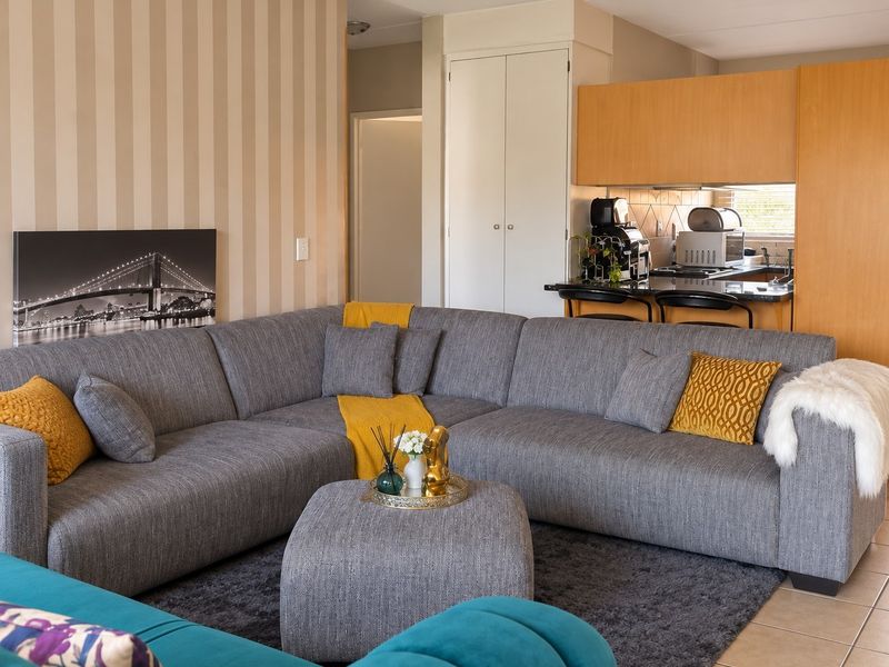 Open-plan living area featuring a functional kitchen with breakfast bar, tiled flooring, and neutral wall finishes, creating a comfortable and connected living space.