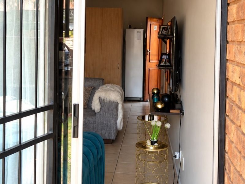 View into a living area featuring tiled floors, exposed brick accents, and a sliding glass door with a security gate.