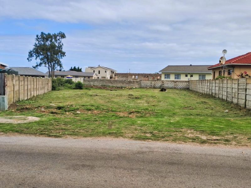 A vacant residential plot featuring established precast concrete boundary walls on both sides, ready for development in a suburban neighborhood.