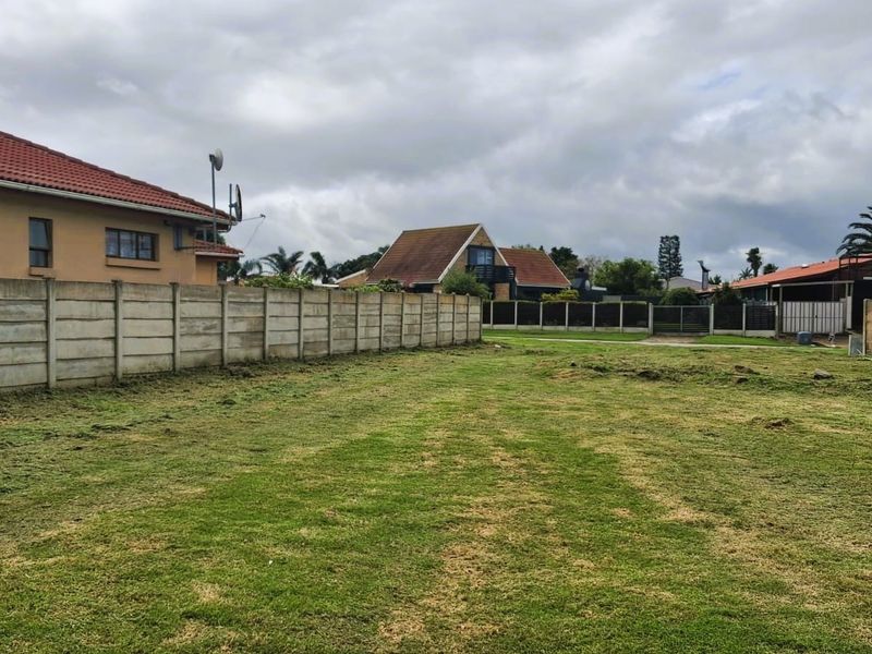 A vacant residential plot featuring a level grass lawn enclosed by precast concrete boundary walls.
