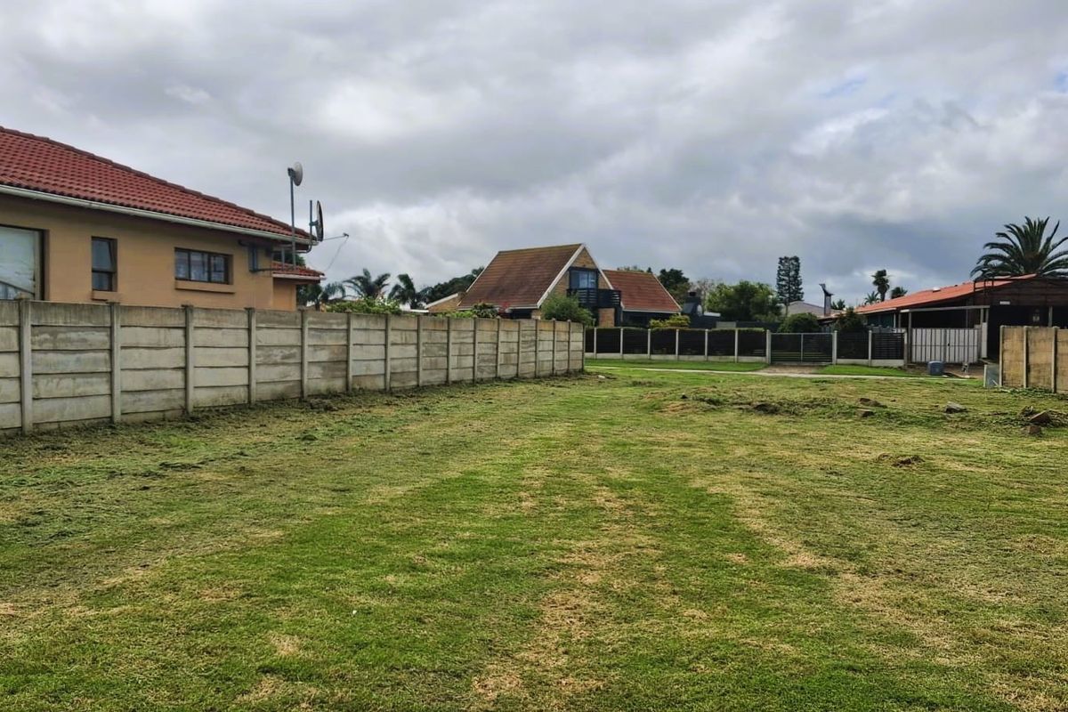 A vacant residential plot featuring a level grass lawn enclosed by precast concrete boundary walls.