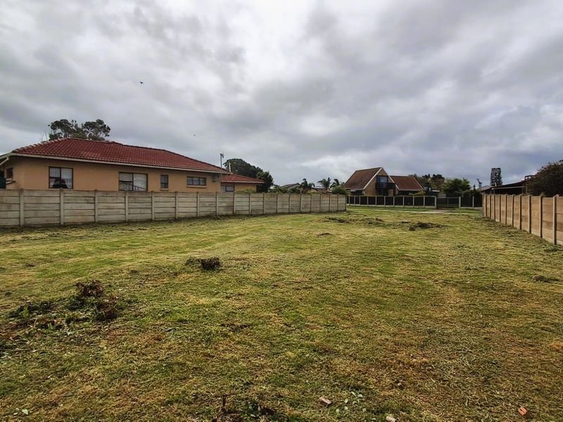 A vacant residential plot featuring cleared grass and secure precast concrete boundary walls, ready for development.