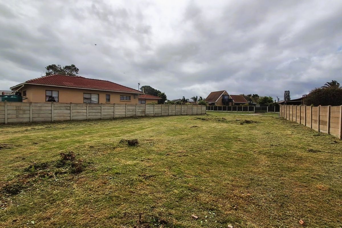 A vacant residential plot featuring cleared grass and secure precast concrete boundary walls, ready for development.