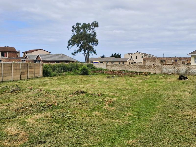 A vacant residential plot featuring a cleared grass area enclosed by precast concrete and block boundary walls in a suburban neighborhood.