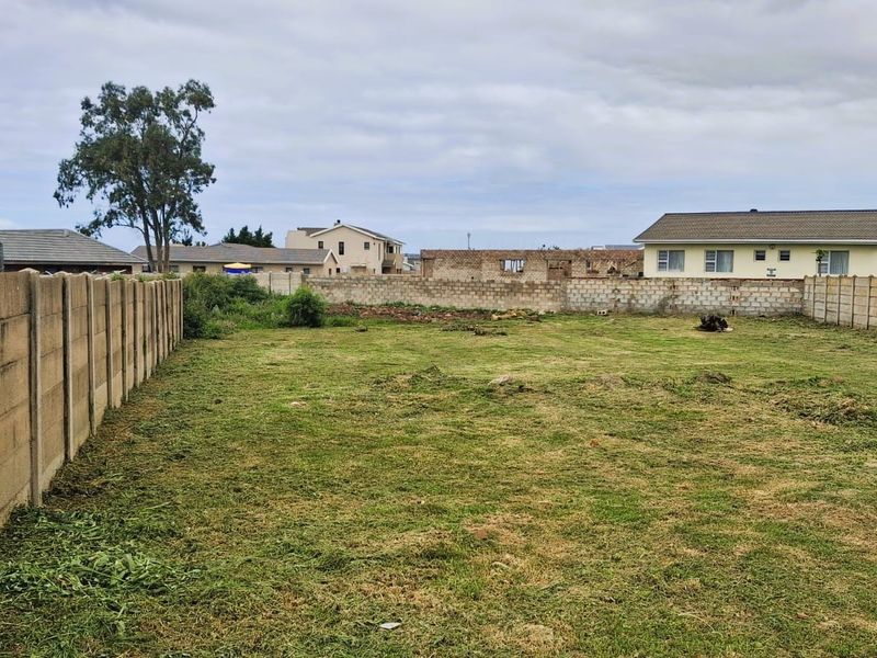 A vacant residential plot enclosed by precast concrete boundary walls, featuring a level grassed area and an existing water storage tank.