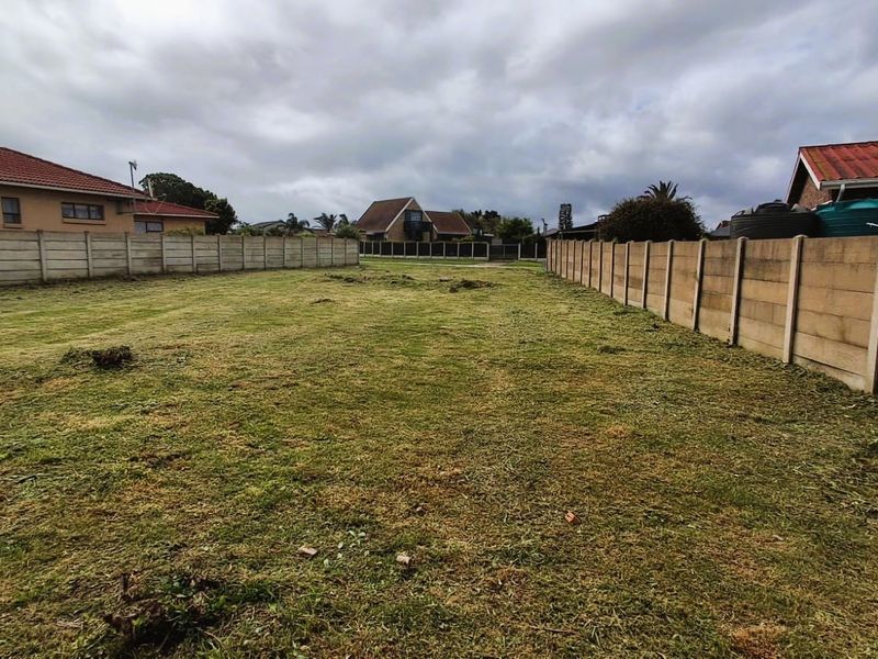 A vacant residential plot featuring cleared grass and precast concrete boundary walls, offering a level space ready for development.