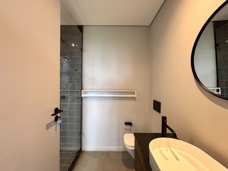 Modern bathroom featuring a glass-enclosed shower, wall-mounted vanity with a vessel sink, and contemporary black fixtures.