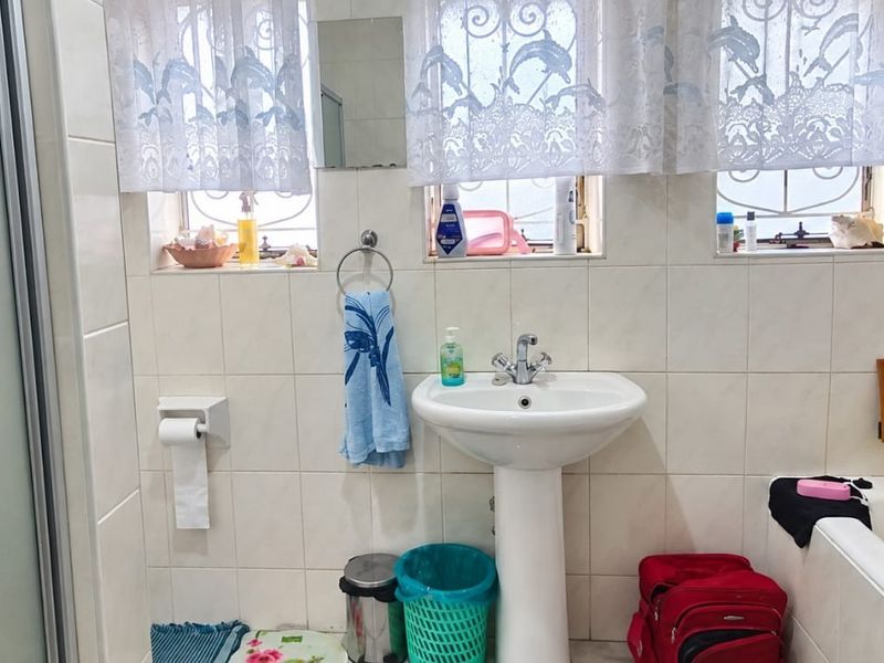 A functional bathroom featuring a pedestal basin, bathtub, and separate shower enclosure with tiled wall finishes.