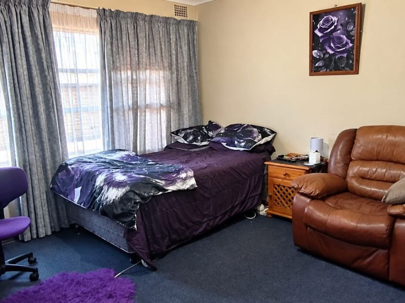 A functional bedroom featuring carpeted flooring and a ceiling ventilation unit, offering a neutral base for potential interior updates.