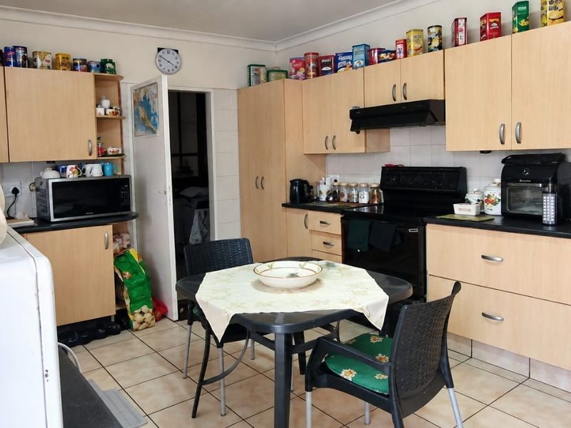A functional kitchen featuring light wood-tone cabinetry, tiled flooring, and a built-in oven with an extractor fan, offering a practical layout for daily use.