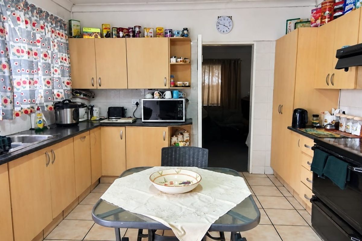Functional kitchen featuring laminate cabinetry, tiled flooring, and built-in appliances, offering a practical layout with ample storage space.