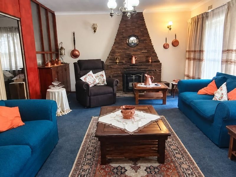 A traditional living room featuring a prominent brick fireplace, coving, and a built-in room divider, offering a classic layout with potential for modernization.