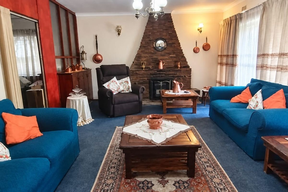 A traditional living room featuring a prominent brick fireplace, coving, and a built-in room divider, offering a classic layout with potential for modernization.