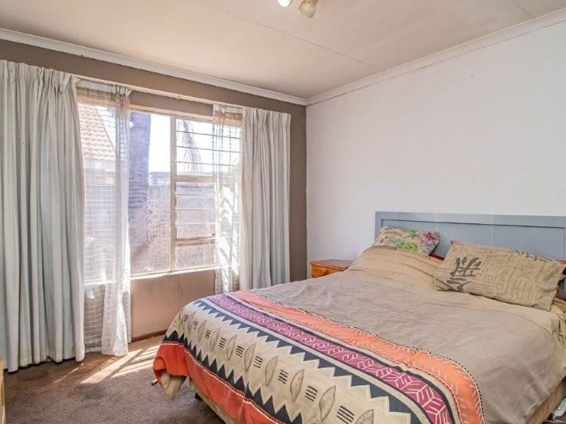 A bedroom featuring louvered windows, carpeted flooring, and coved ceilings, offering a functional space ready for cosmetic updates.