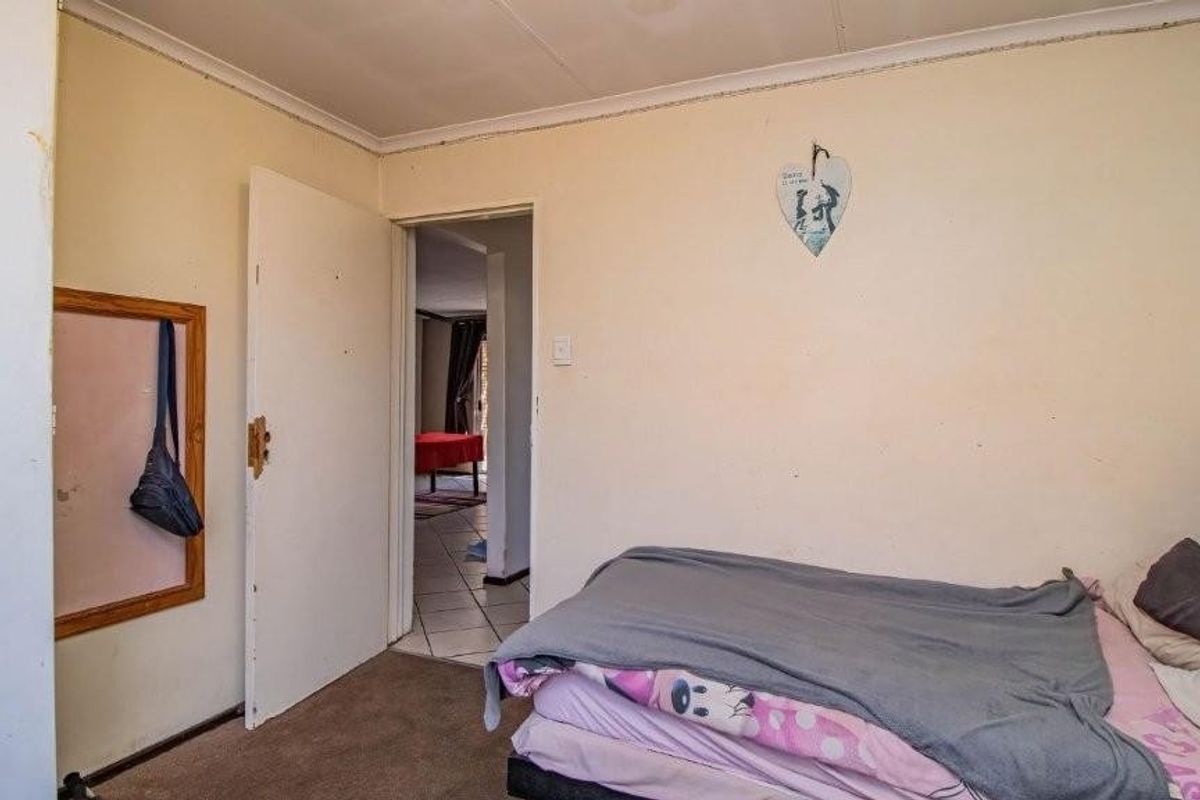A bedroom featuring carpeted flooring and standard internal doors, showing signs of wear and requiring cosmetic updates to improve its overall condition.