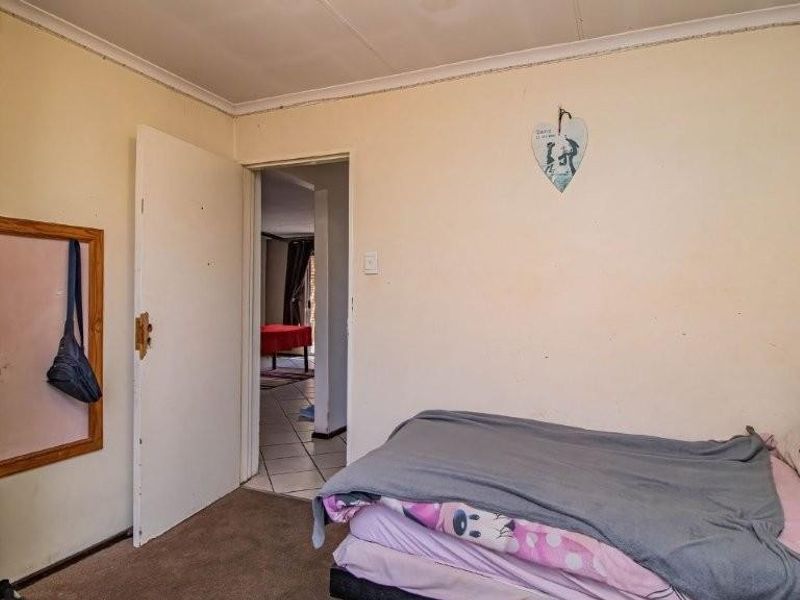 A bedroom featuring carpeted flooring and standard internal doors, showing signs of wear and requiring cosmetic updates to improve its overall condition.